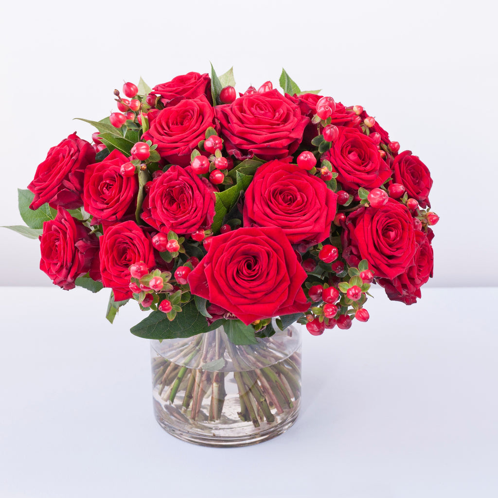 Grand prix red roses with hypericum berries and foliage in a vase