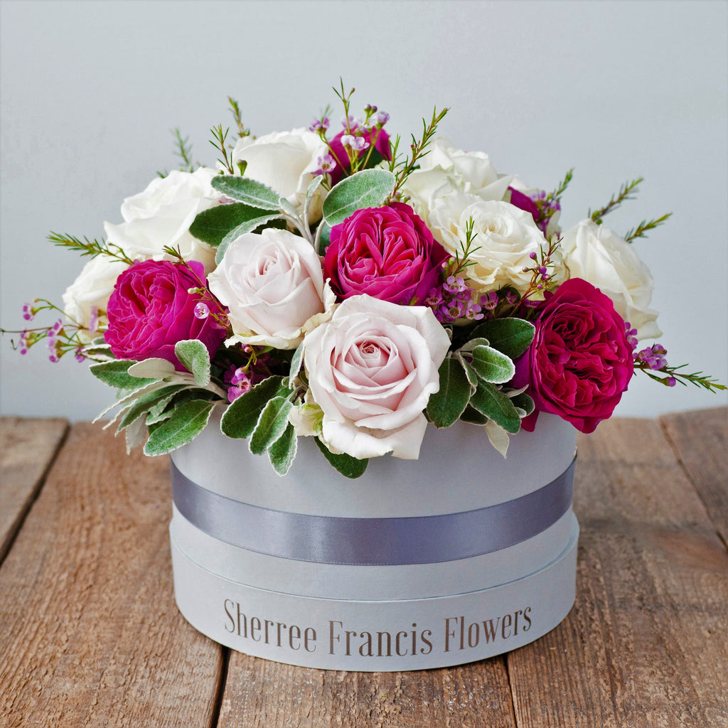 Hat box filled with cerise pink and light pink roses and foliage