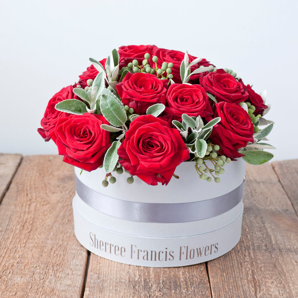 Image of grey hat box filled with red roses and foliage 