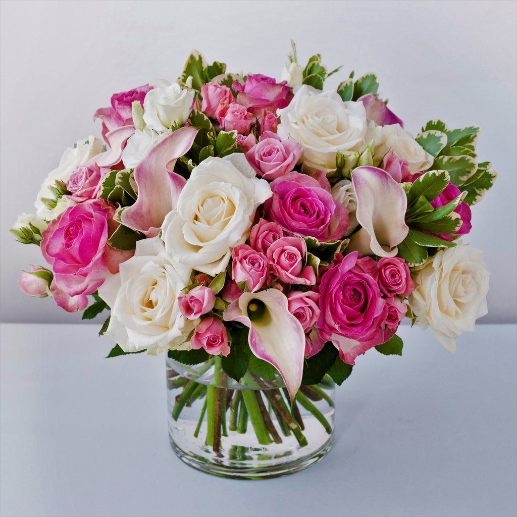 Bubblegum pink roses, white avalanche roses, white lisianthus, pale pink calla lilies in a vase